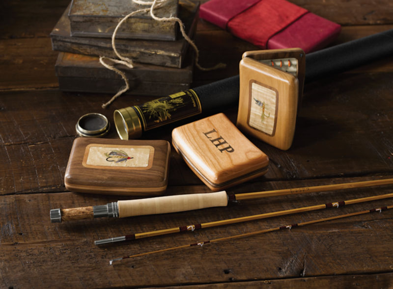 A bamboo fly rod displayed next to two hand-carved wooden fly boxes.
