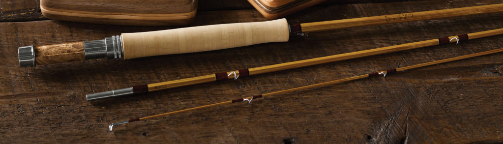 A bamboo fly rod displayed next to two hand-carved wooden fly boxes