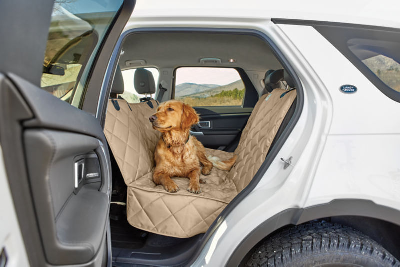 A wet golden retriever lays on a backseat protector in an SUV.