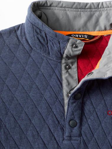 A detail of a quilted snap sweatshirt in navy with red and gray highlights.