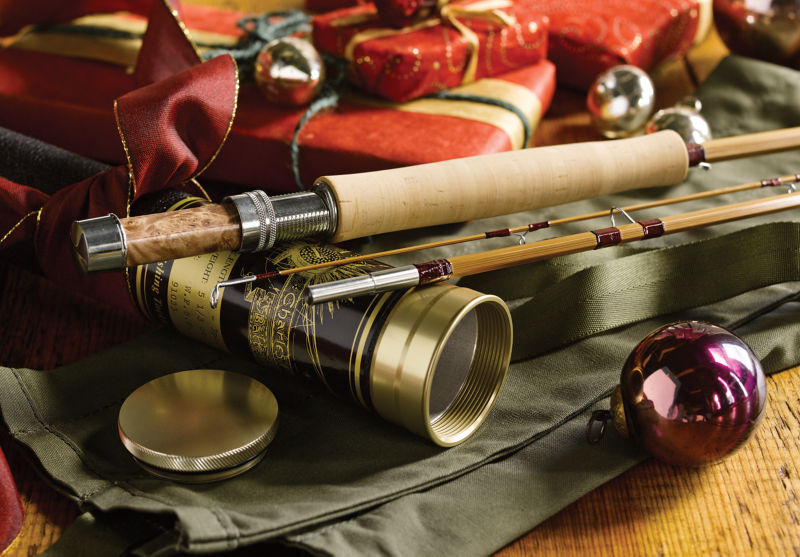 A bamboo fly rod leaning on its ornate metal tube.