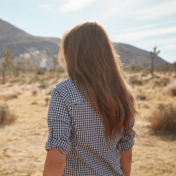 A woman in checkered shirt in the desert.