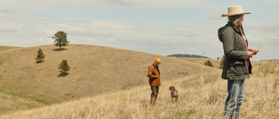 A man and woman in a field with their dog.