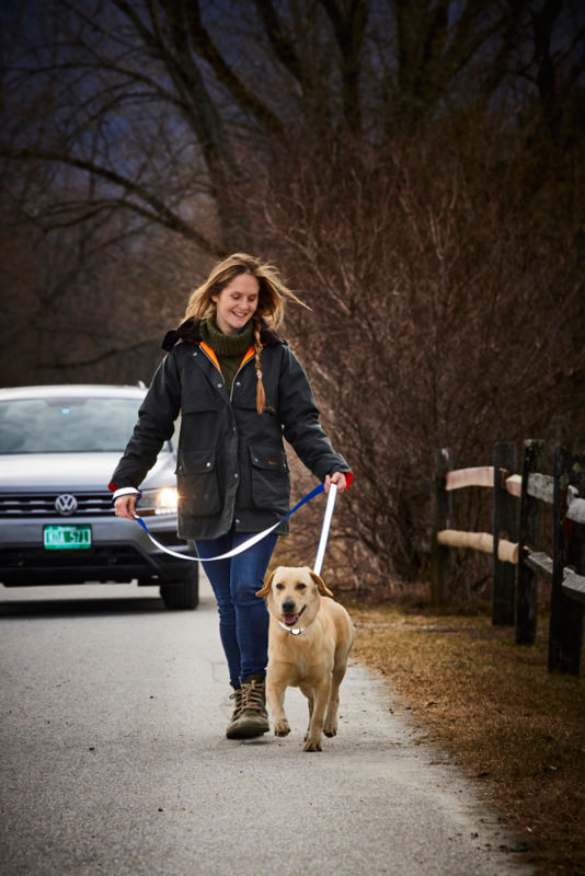 A woman walking her dog at dusk using the reflective collar and leash.