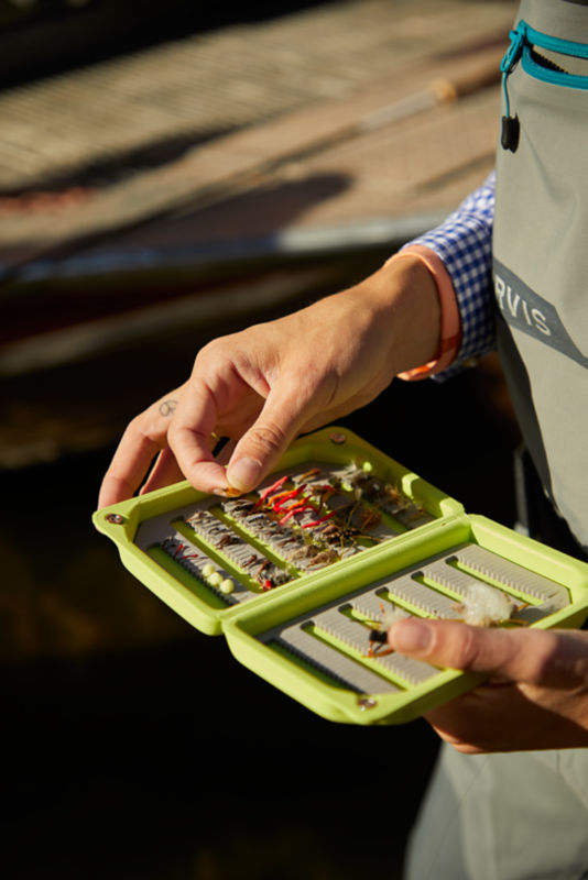 An angler picks through her foam fly box.