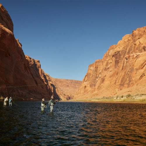 western river canyon with anglers wading in the distance