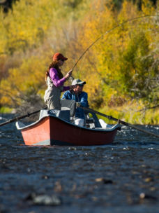 Two anglers fly fishing from a row boat on the water 