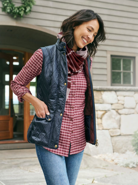 Woman in Navy Barbour® Wray Gilet checks her pockets as she walks out the door.