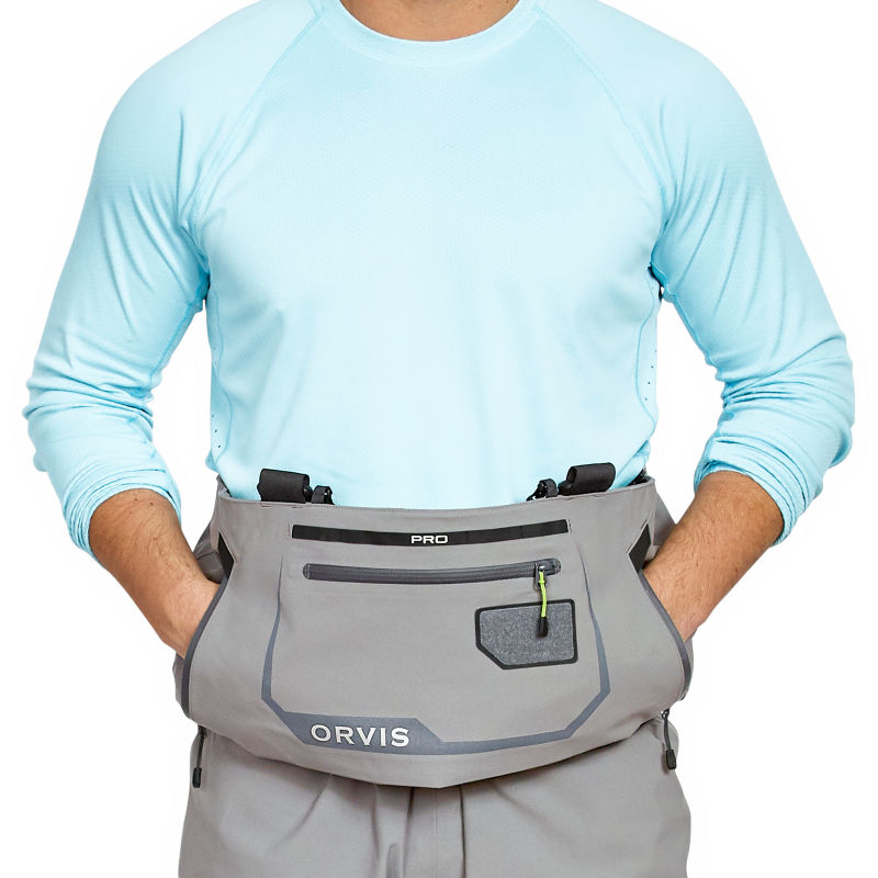An angler wearing Orvis PRO Waders places their hands in the kangaroo pocket.