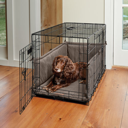 A brown dog laying down in a dog crate in a living room.