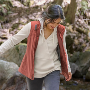 Woman in PRO Insulated vest walks up a rocky riverbed.