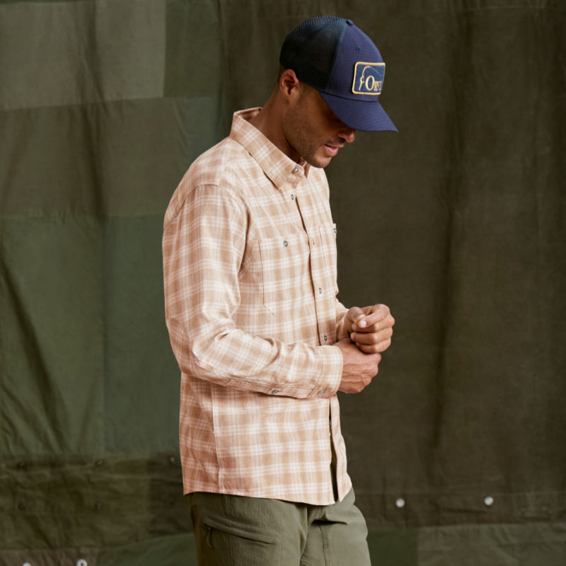 A model wearing a beige and white plaid shirt and olive colored khakis