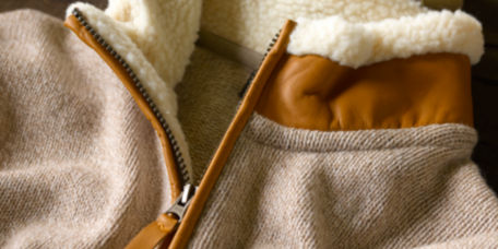 A close-up of a Sherpa collared wool sweater in cream and tan