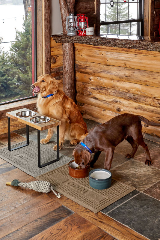 Two dogs eat out of their bowls over separate Personalized Recycled WaterHog&reg; Grid Pet Placemats.