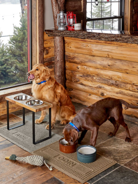 Two dogs eat out of their bowls over seperate Personalized Recycled Water Trapper® Grid Pet Placemats.