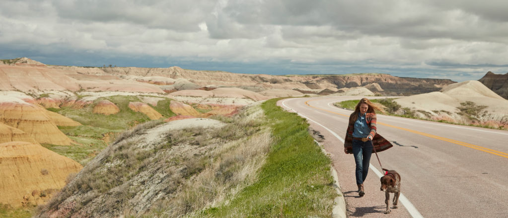 Woman walking dog down the road in the badlands.