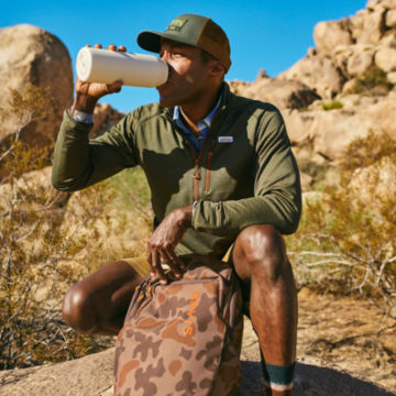 Man wearing Horseshoe Hills Quarter-Zip takes a drink on the trail.