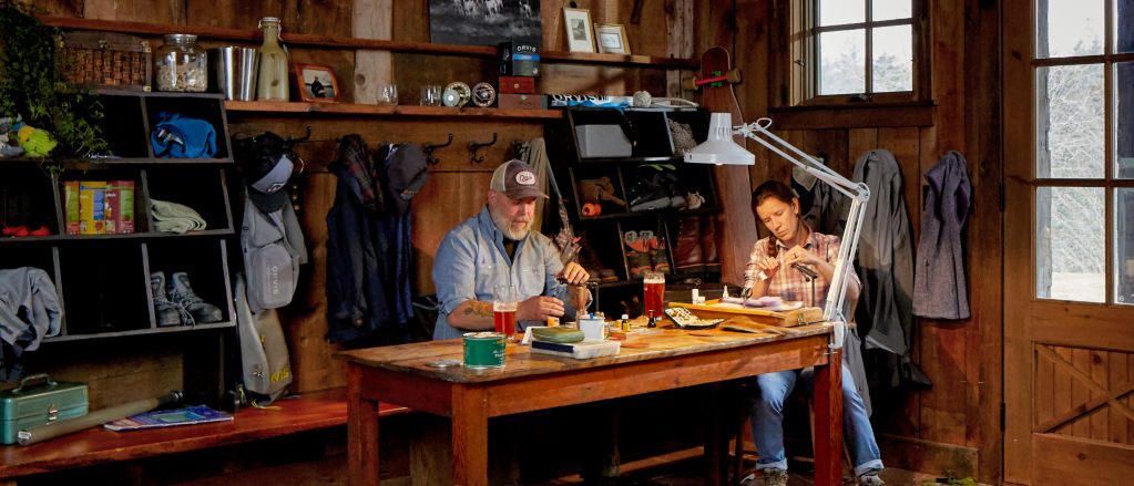 Two people sitting at a table tying flies
