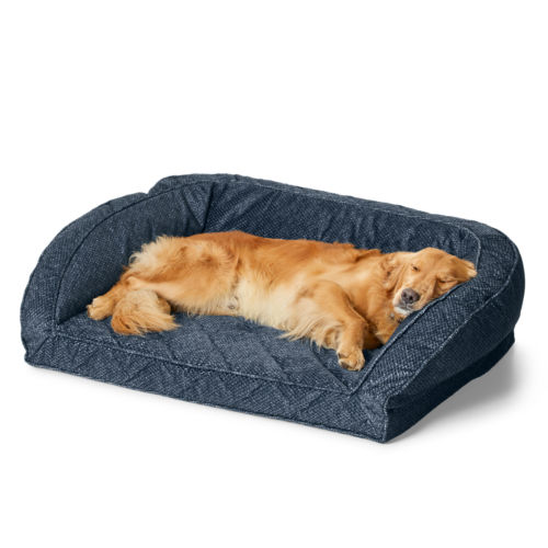 A golden retriever sleeps on a blue bolster dog bed