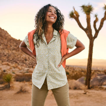 A woman takes a morning walk in the desert with her sweatshirt slung over her shoulders.