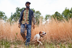 A man and dog walking through a field