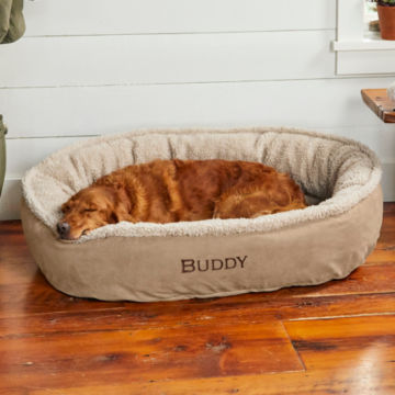 A dog takes a nap in its wraparound bed.