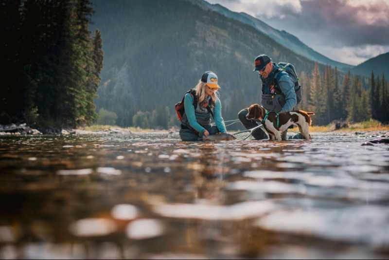 Timbre and D'Arcy with their dog, North, release a fresh-caught fish back into a river