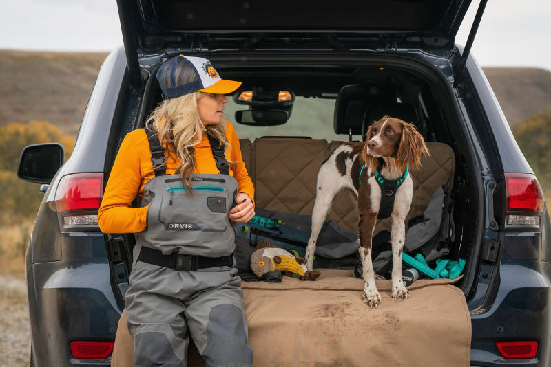 A woman and her dog sitting in the back of a car
