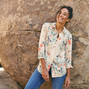 Woman in Everyday Printed Silk Shirt leans against rock.