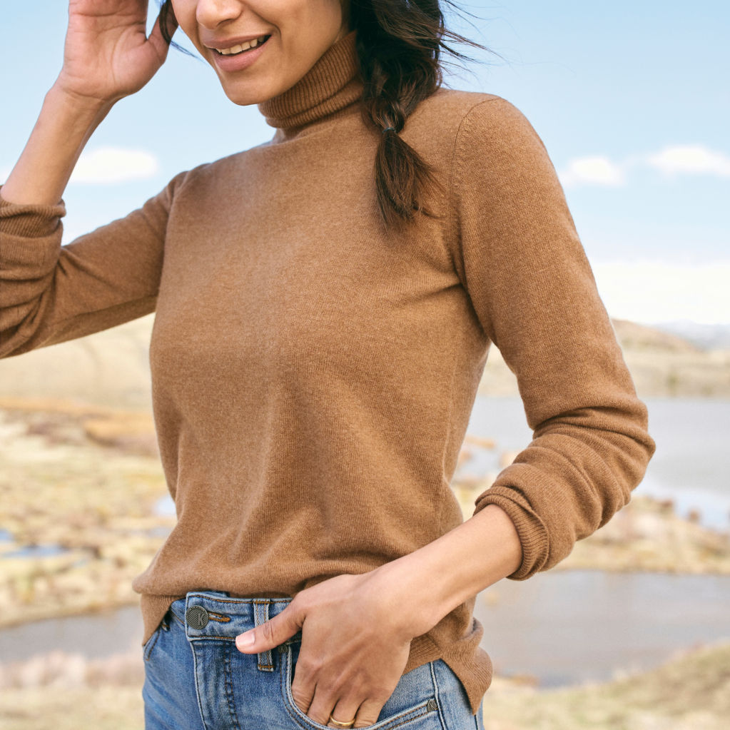 Woman with Classic Cashmere Turtleneck Sweater in Dark Vicuna poses outdoors.