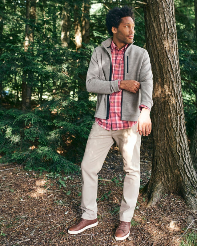 Man in Grey Lewiston Sweater walks through the forest.