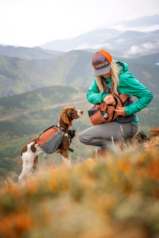 Woman and dog loaded with Tough Trail&trade; gear stop to have a snack on a steep, rocky trail.