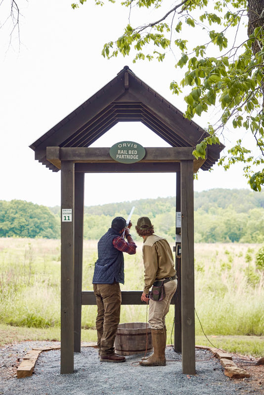 An instructor teaches a new wingshooter at a shooting stand.
