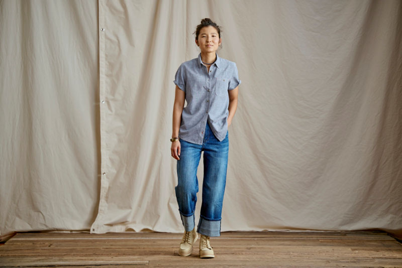 A model wearing a light blue button-down over blue jeans.