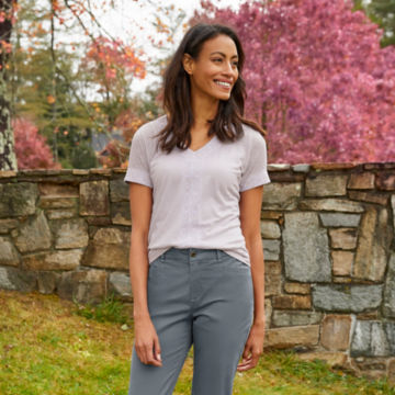Woman poses in Shoreline Explorer Embroidered Tee outdoors next to a rock wall.