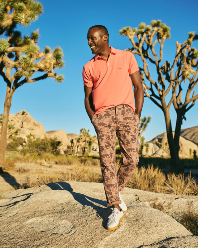 Man scrambles on boulders wearing a polo and shorts