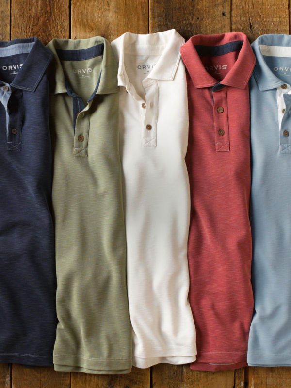 A color range of polos laid on a wood background.