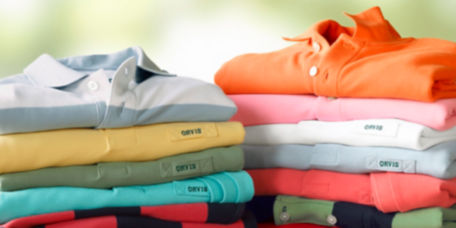 Two stacks of folded polo shirts in a variety of colors