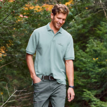 Man in Orvis Signature Polo walks through a forest.