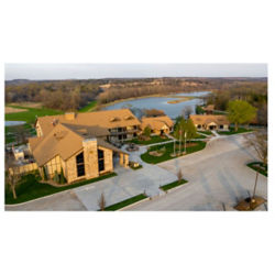 An aerial view of a warm stone lodge on a river bank.