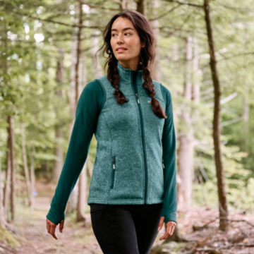 Woman in R65 Sweater Fleece Vest Walks through the woods.
