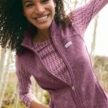 Woman in purple print Long-Sleeved Relaxed Perfect Tee smiles at the camera as she walks through the woods.
