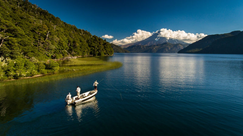 Three anglers in a boat fishing at a scenic area of Patagonia.