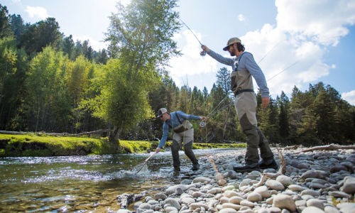 Jackson Hole Fly Fishing School netting a fish in a rocky river.