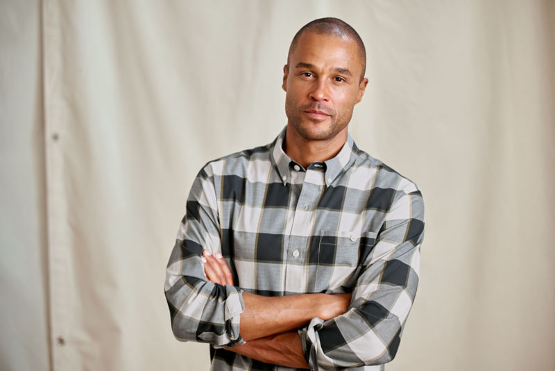 A model wearing a black and white plaid button-down shirt.