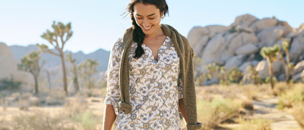 A woman wearing a print button-down shirt hiking in a desert landscape