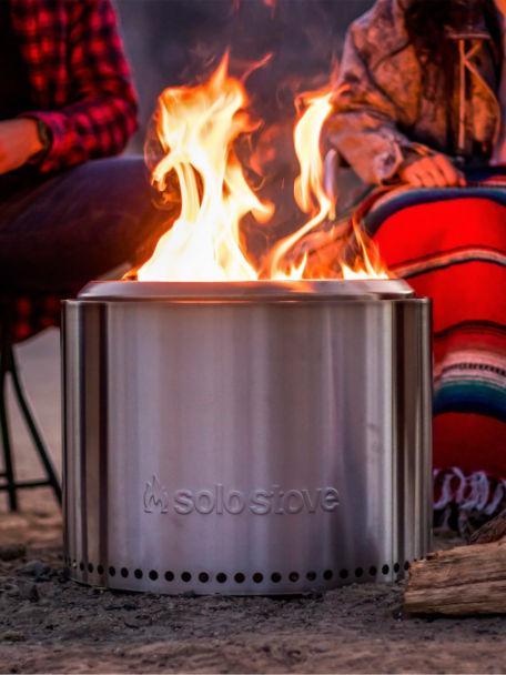 A couple of folks bundle up around a Solo Stove at night.