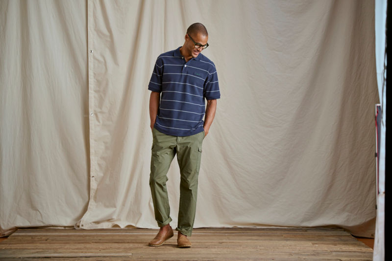 A model wearing a striped polo shirt with olive cargo pants.