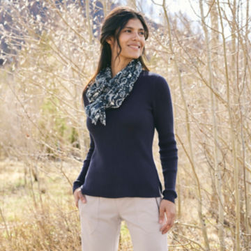 Woman in V-Neck Ribbed Sweater looks out on the landscape as she walks through a field.