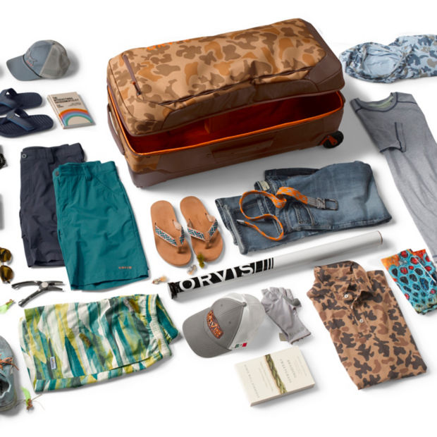 A wide assortment of travel clothes and shoes with a suitcase